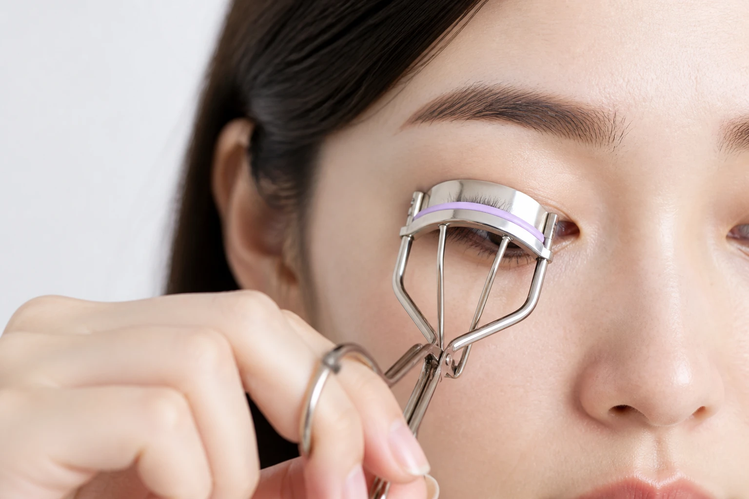 Femme utilisant un recourbe-cils en métal sur ses cils naturels, gros plan beauté en lumière naturelle