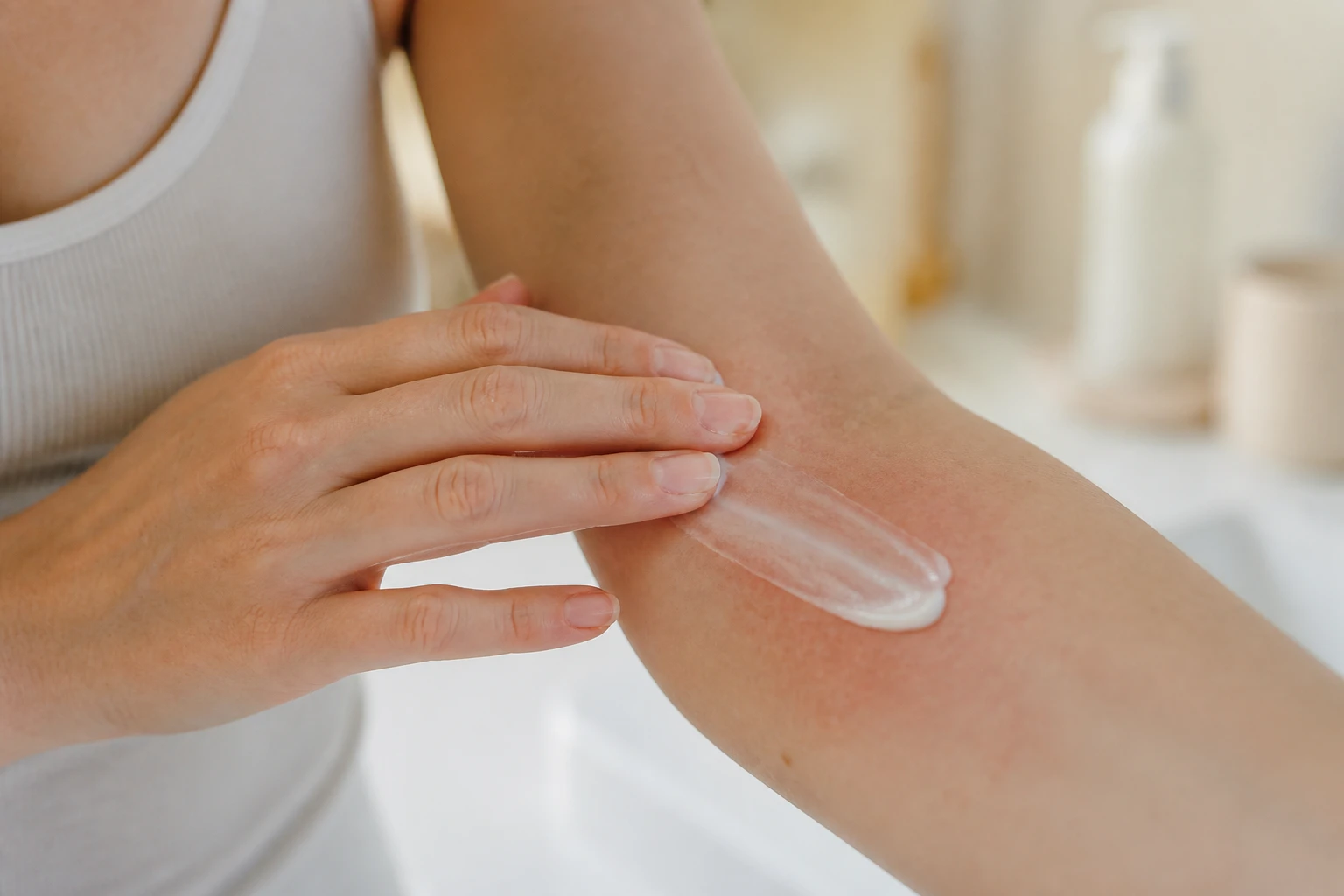 Femme appliquant délicatement une crème réparatrice sur une zone de peau lésée et sensible