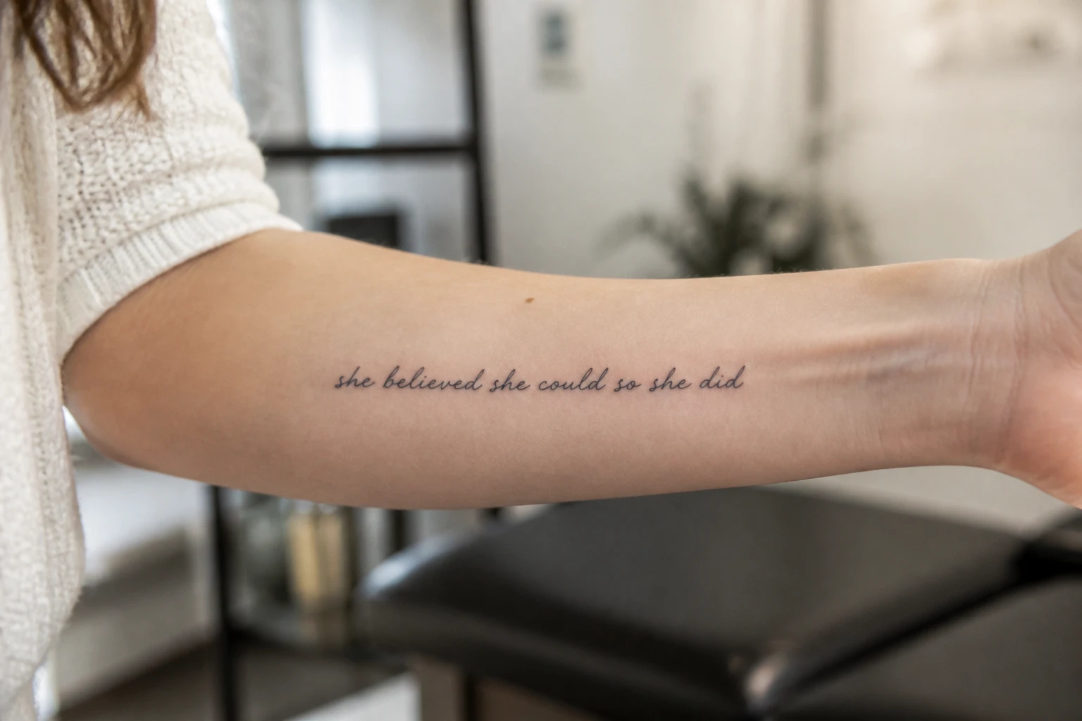 Avant-bras de femme avec un tatouage phrase force en écriture cursive fine